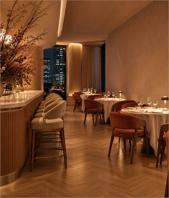 Warmly lit Netrisok dining room with terracotta chairs and city view